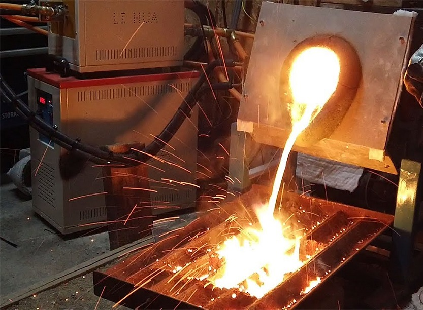 Metal incandescente é derramado de um cadinho em um molde, gerando faíscas intensas em um ambiente industrial.