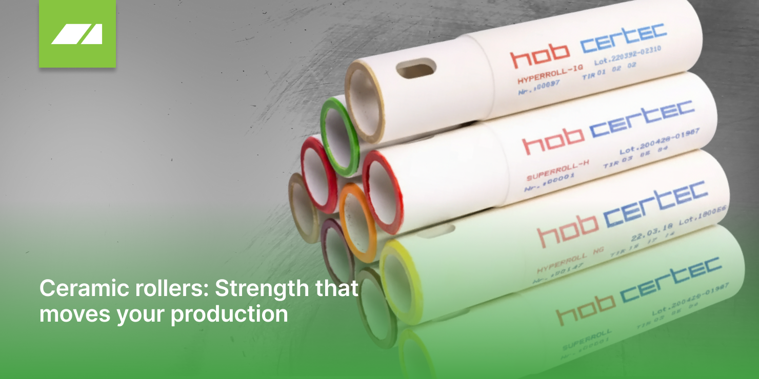 Ceramic rollers: Strength that moves your production. Close-up image of three stacked white ceramic rollers with colorful rings on the ends (red, green, yellow, orange). The rollers are branded 'hob certec' and have product details printed on them. There